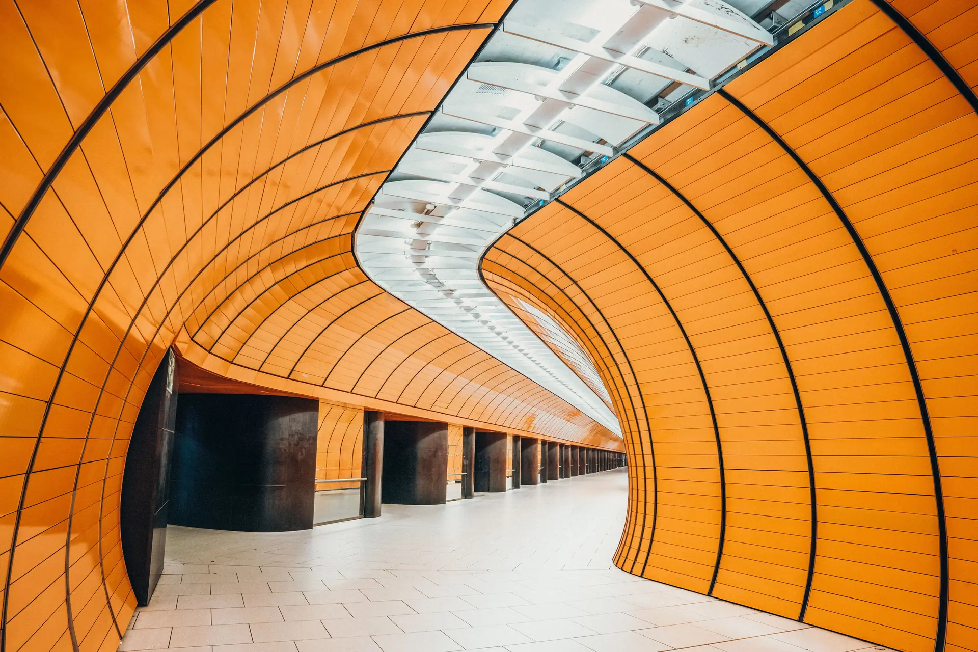 Curved orange-panelled metro tunnel leading into the distance